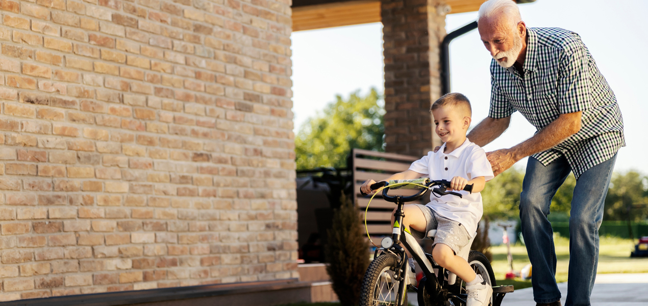An elderly man and a young boy cycling together, enjoying their time outside.